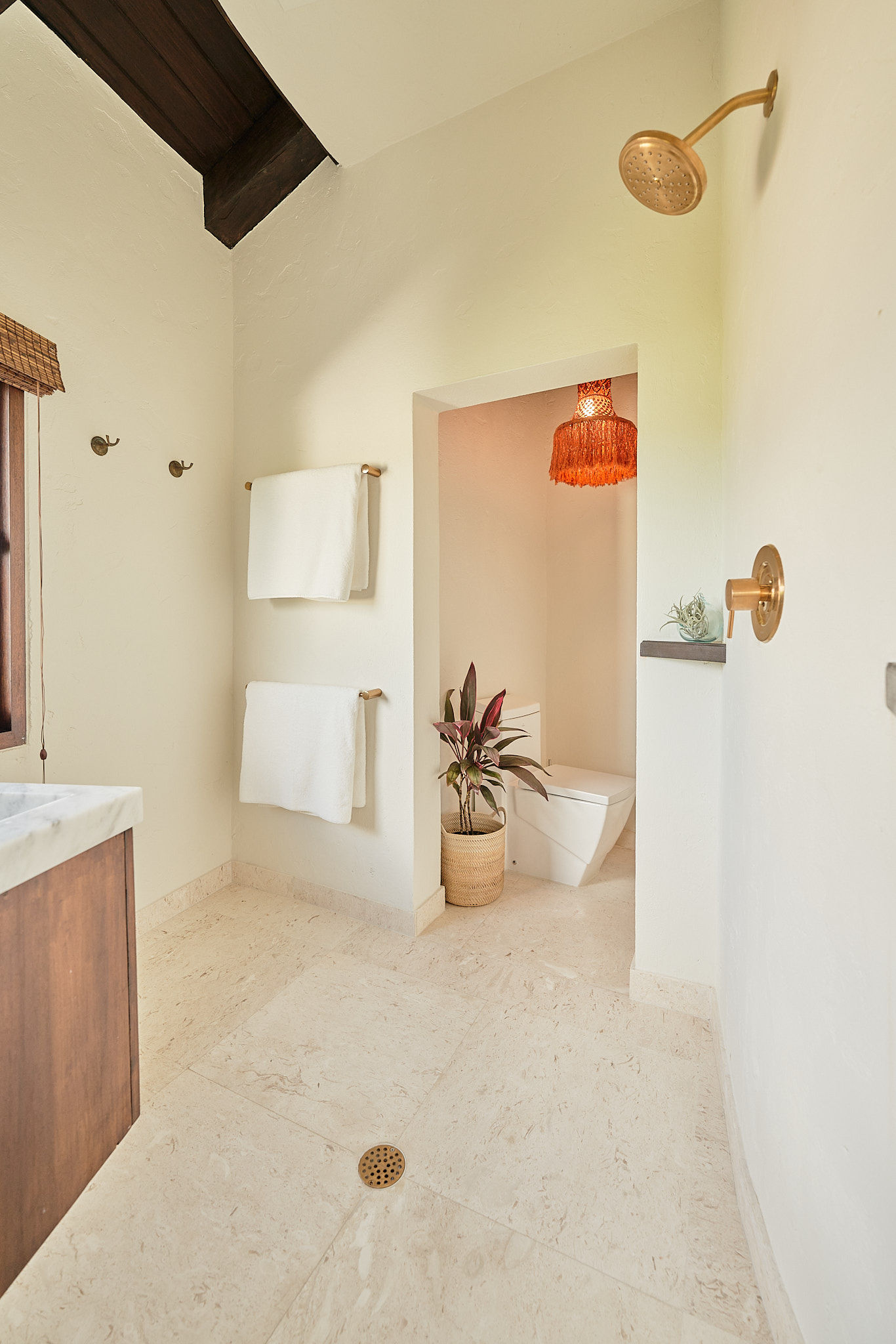 image A relaxing shower with natural stone flooring, wicker pendant light, and minimalist coastal décor.