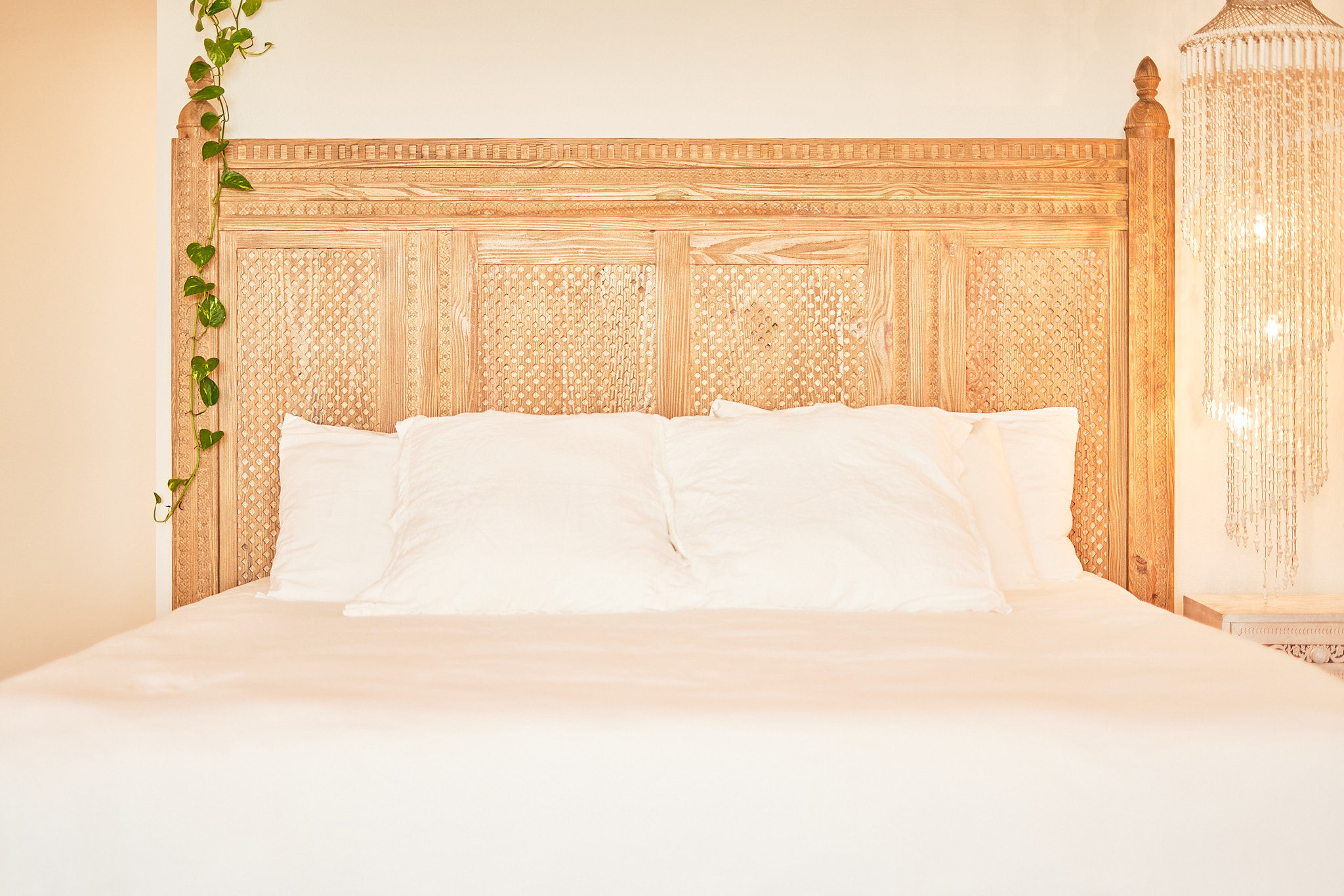 image Hand-carved wooden headboard adds charm to the cozy bedroom setup.