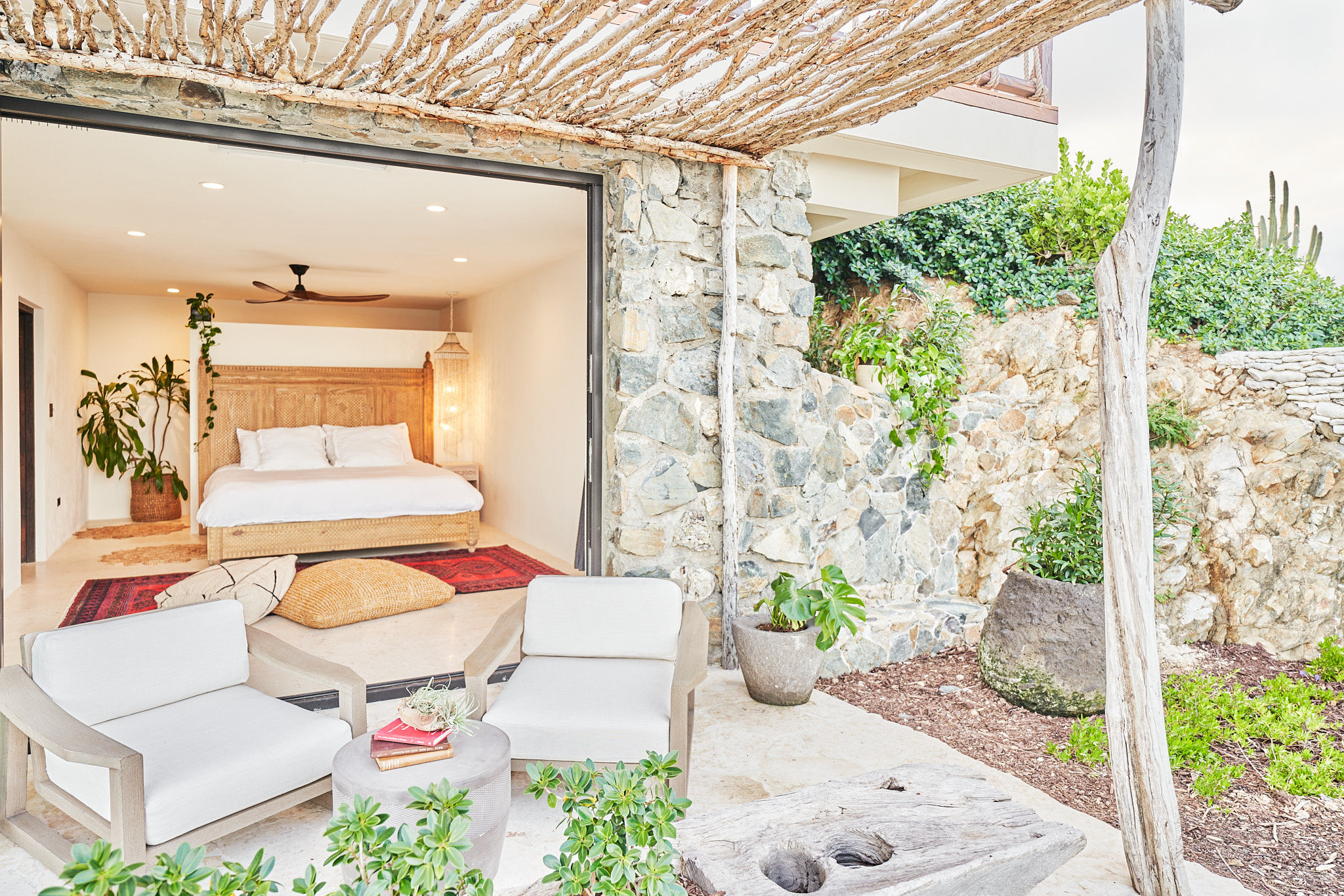 image Seamless indoor-outdoor living with a cozy bedroom opening onto a private stone patio and shaded lounge area.