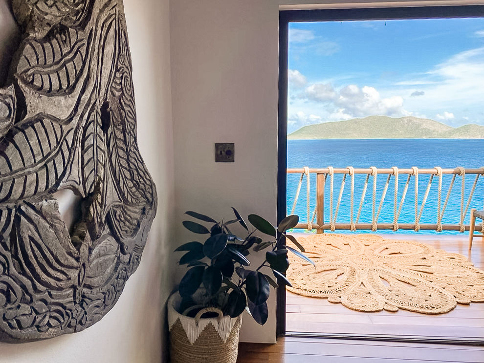image Stylish interior with carved wall art and direct access to ocean-view balcony.