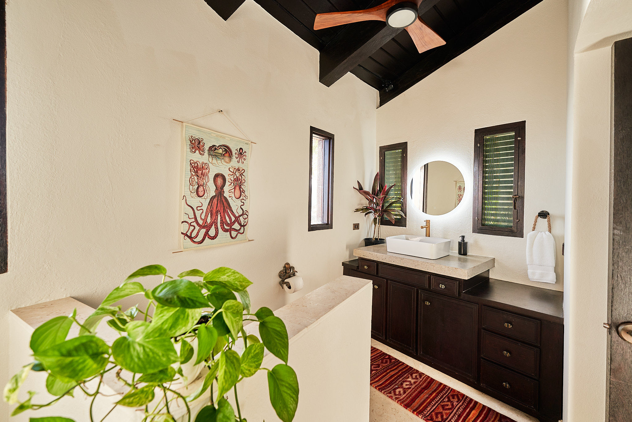 image Spacious bathroom with double vanity, dark wood cabinetry, and boho-chic touches.