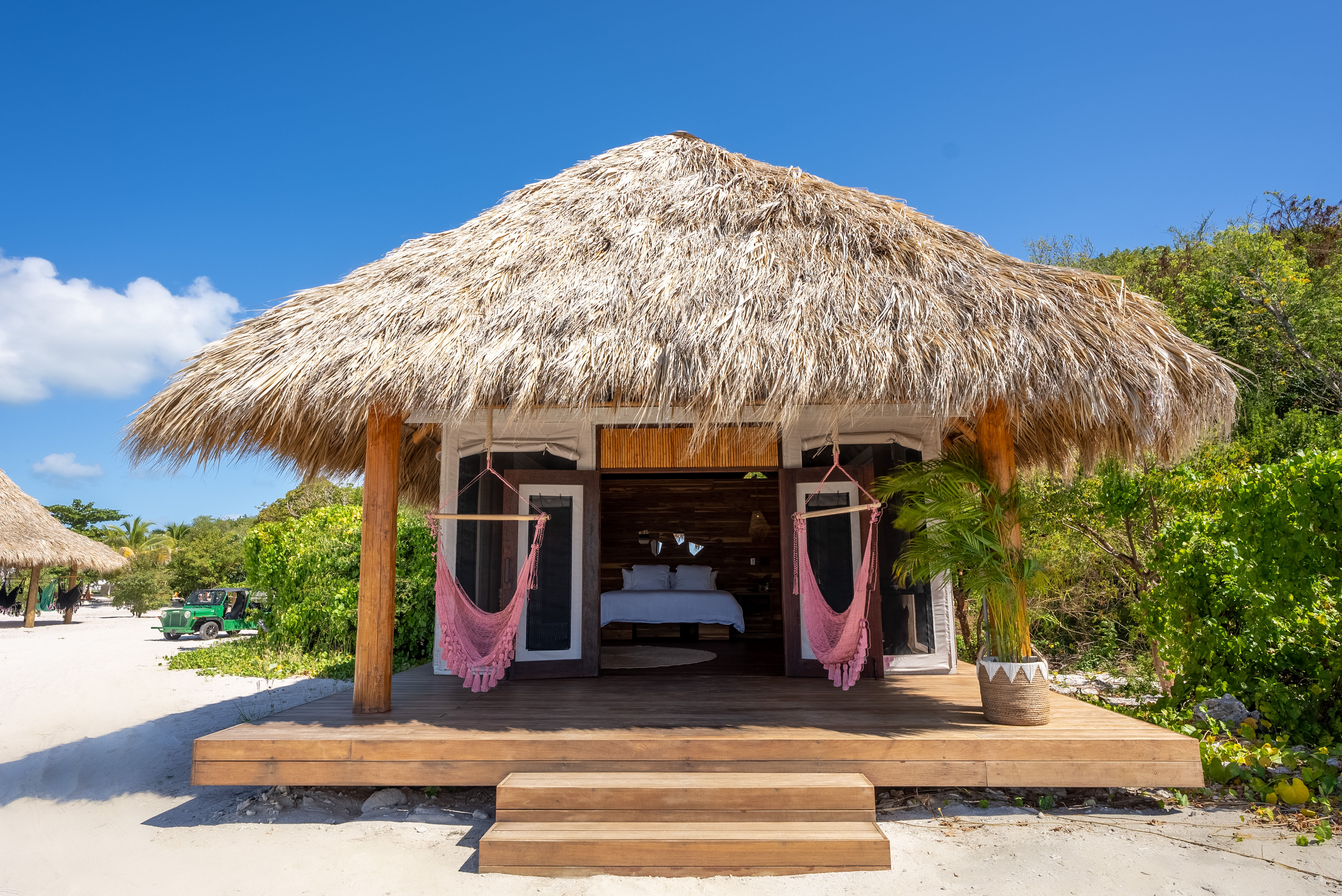 image Thatched-roof beachfront teepee nestled in tropical greenery with hammock swings.