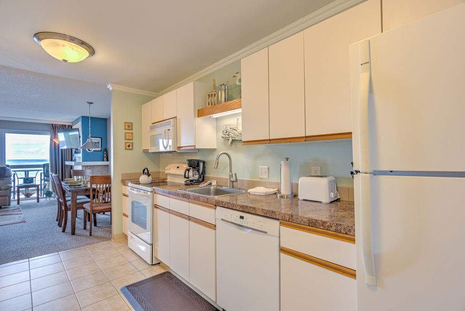 image The full kitchen is equipped with all necessary amenities, providing guests with a convenient space to prepare meals while enjoying ocean views.