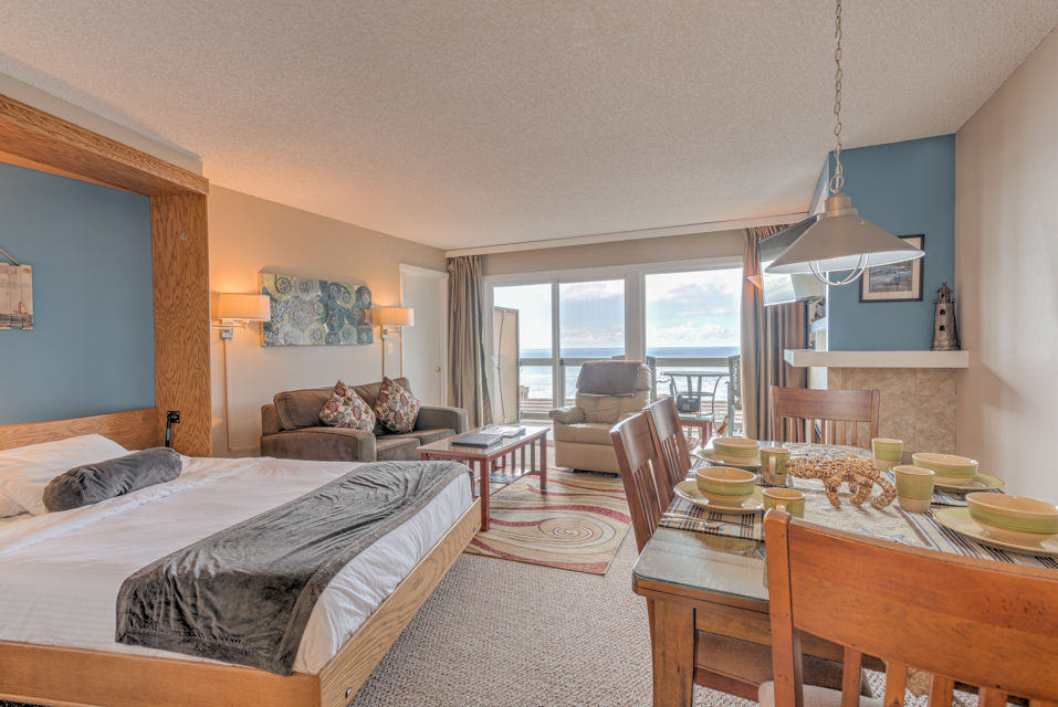 image The Ocean View Queen Bed Studio features a cozy queen Murphy bed alongside a comfortable sitting area and a dining space with elegant decor.