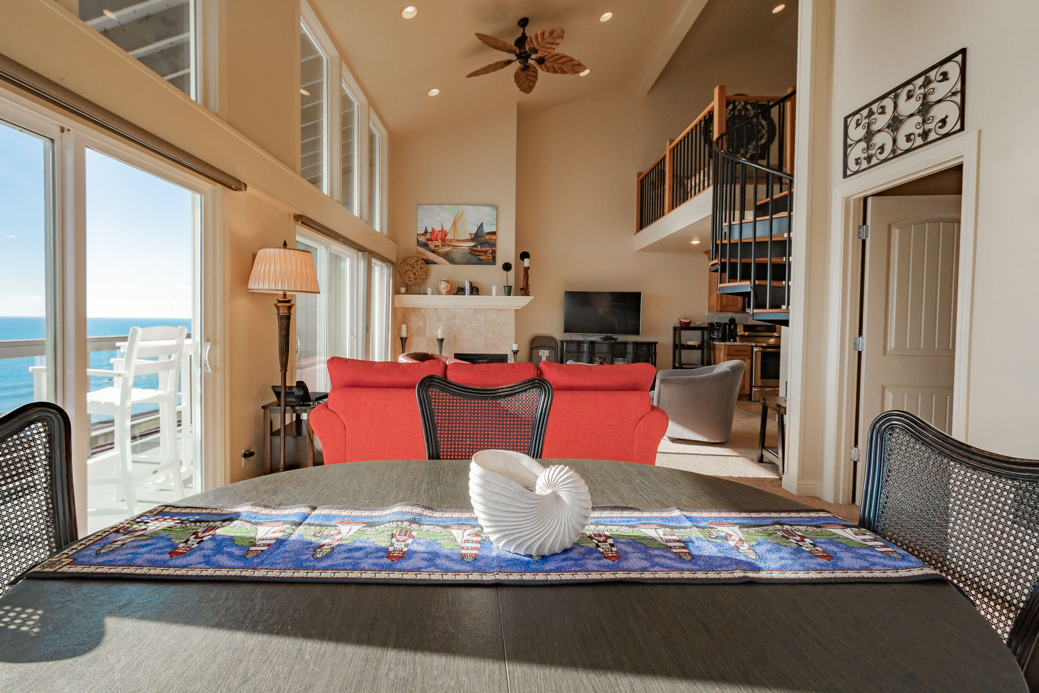 image The Coastal Villa features a bright open-concept living area with vaulted ceilings, ocean-view windows, and a dining table set for four.