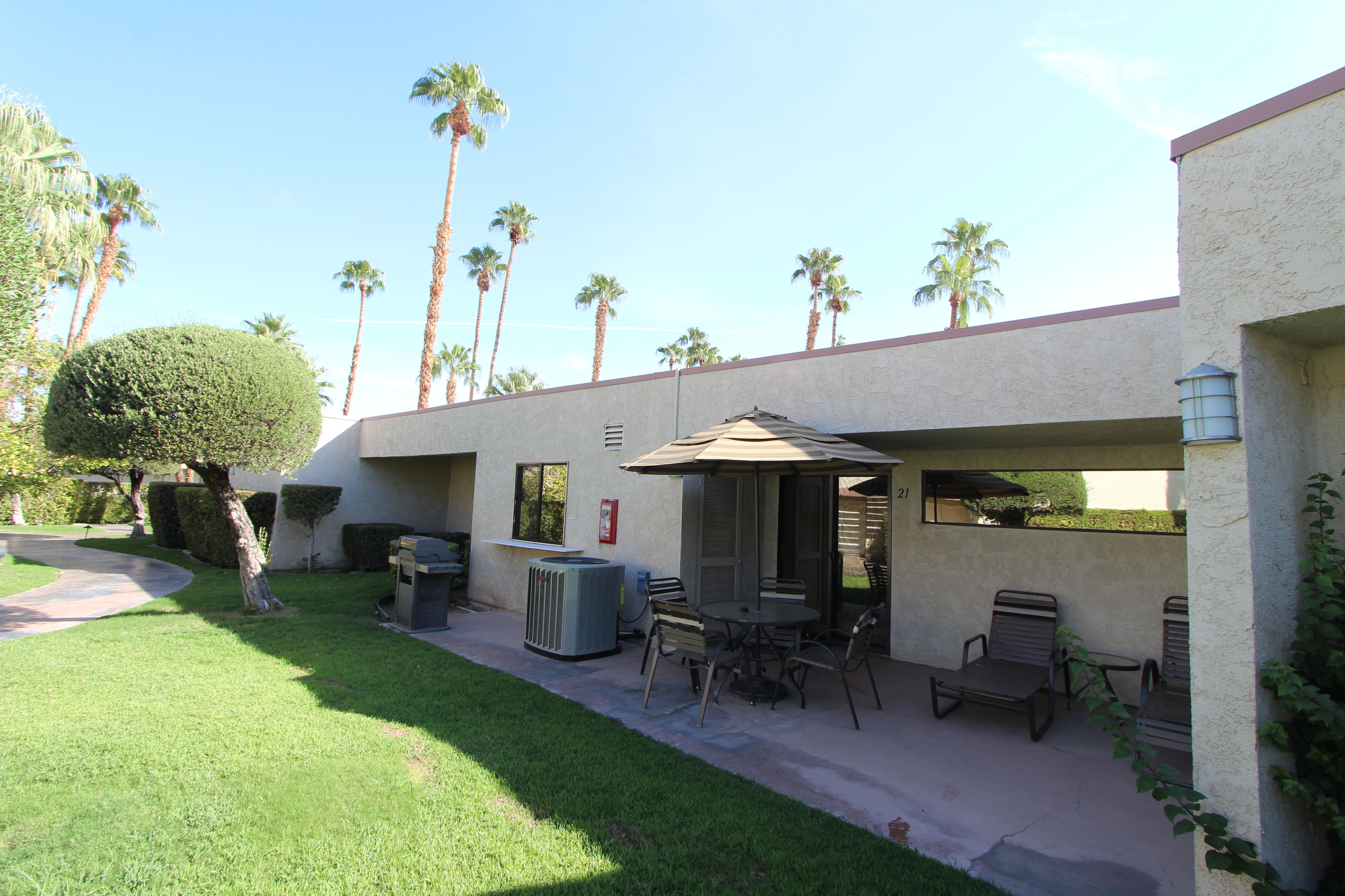 image The exterior view reveals a relaxing patio surrounded by well-manicured landscaping, complete with outdoor seating and palm trees in a picturesque setting.