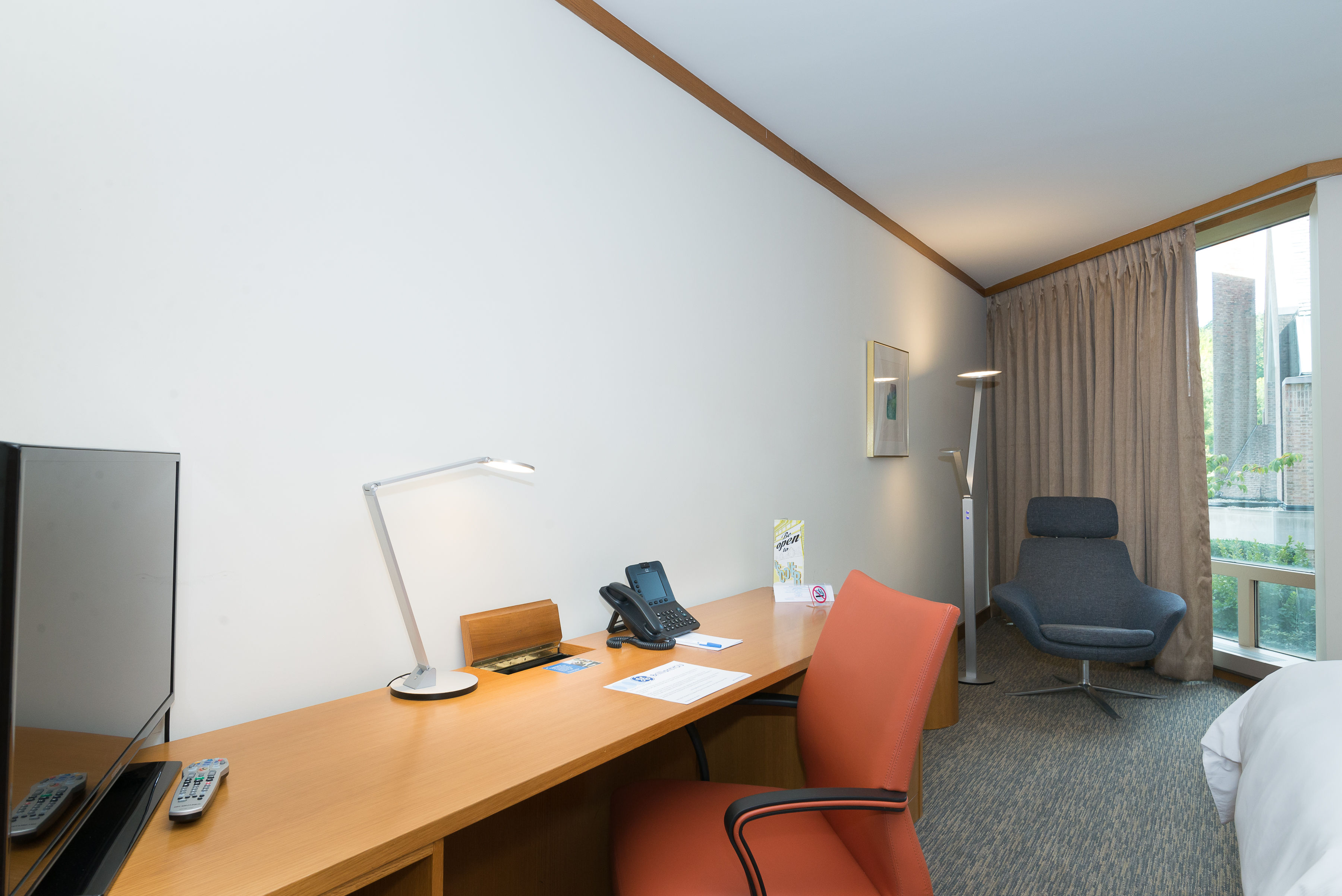 image The workspace in this guestroom combines functionality and style, complete with a sleek desk, phone, lamp, and flat-screen TV, perfect for business travelers.