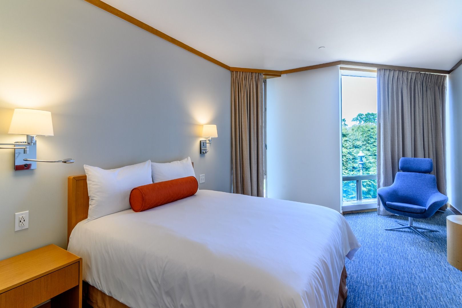 image Experience comfort and tranquility in this modern guestroom featuring a queen bed, natural light, and a cozy seating area for relaxation in the heart of Hudson Valley.