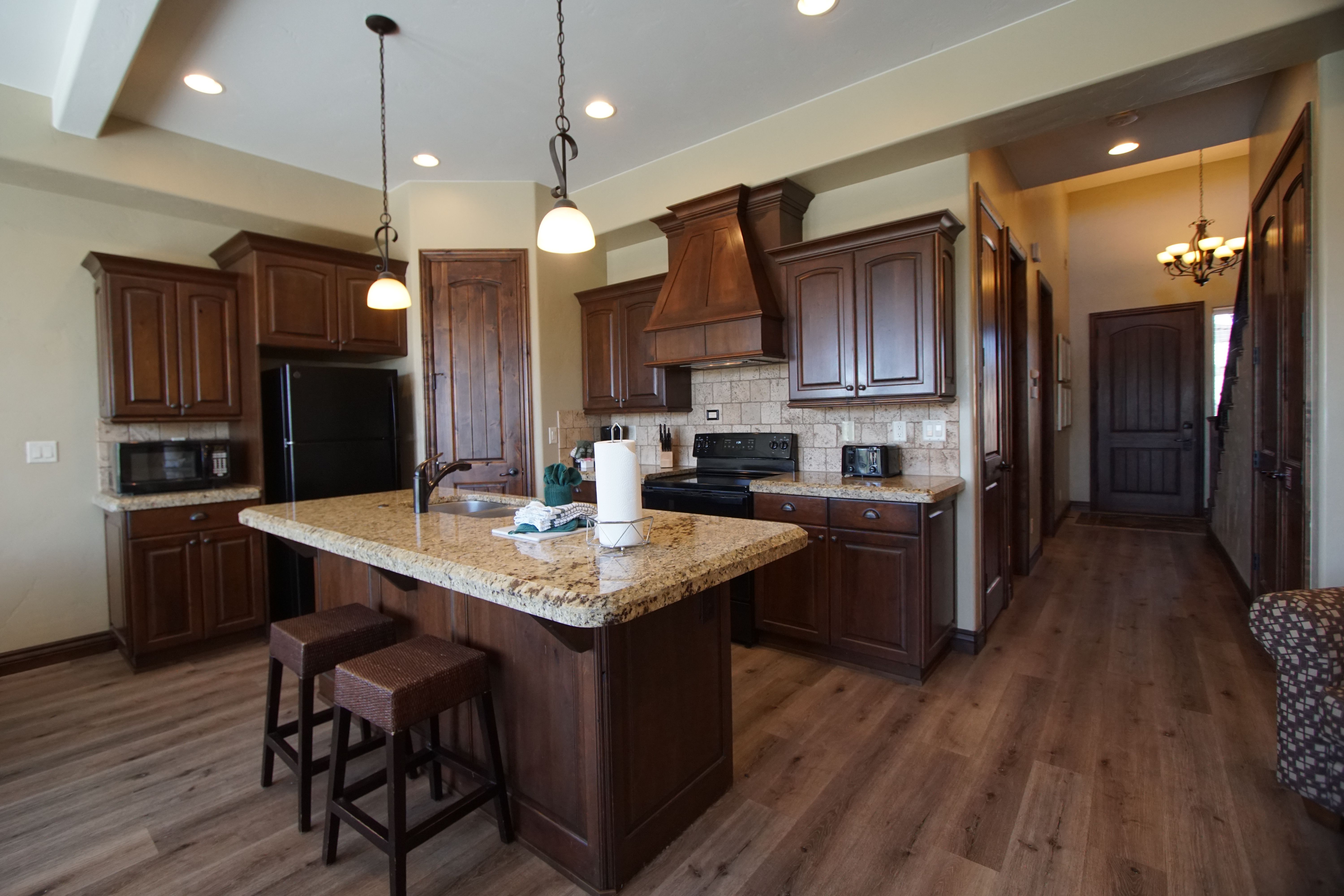 image Modern kitchen with full appliances, island seating, and warm wood cabinetry.
