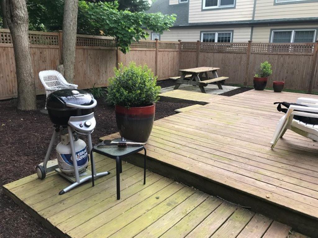 image Spacious backyard deck with grill and picnic table, perfect for outdoor dining and evening BBQs.