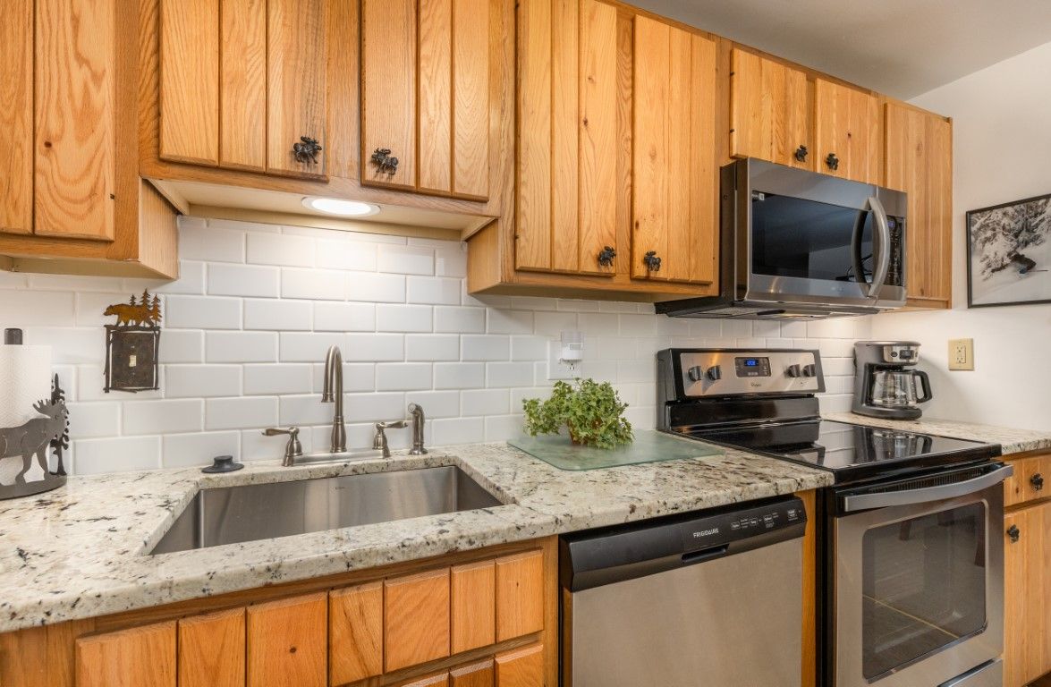 image The modern kitchen features rustic wooden cabinets, sleek appliances, and a spacious granite countertop, perfect for meal preparation.