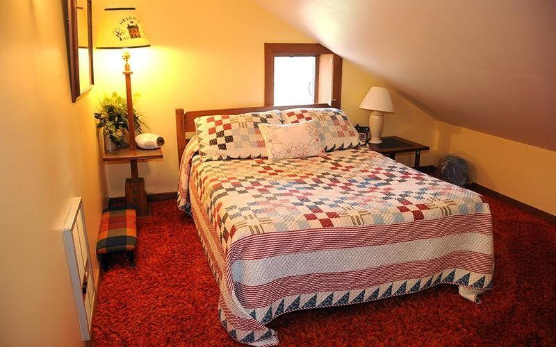 image The inviting loft bedroom showcases a colorful quilt atop a bed, complemented by cozy decor and a bright window.