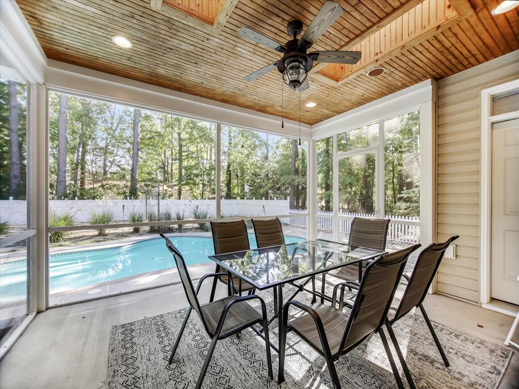 image Screened porch features a dining table, ceiling fan, and views of the pool for comfortable outdoor meals.