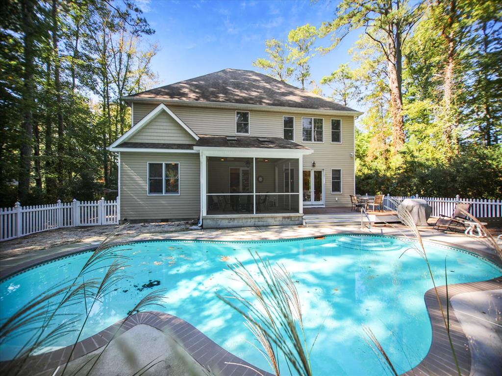 image Rear exterior view shows a private backyard pool with surrounding deck space and the spacious two-story home nestled among mature trees.