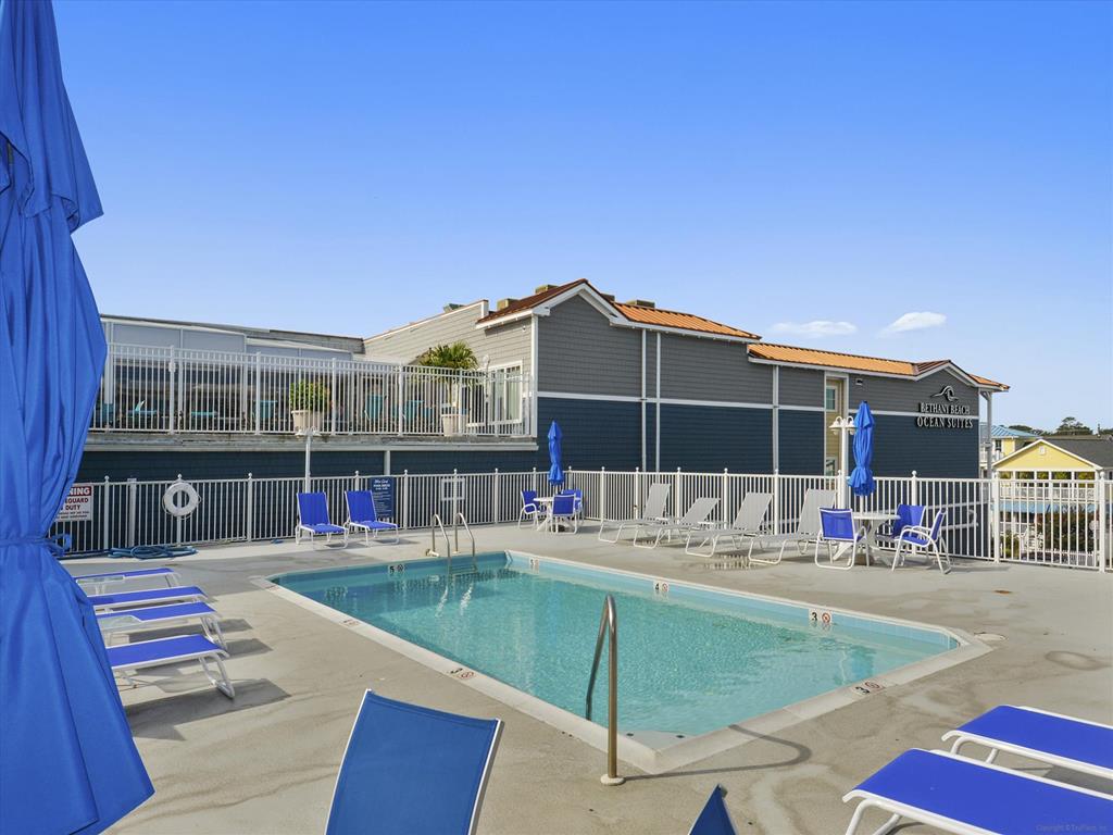 image Unwind at the community pool surrounded by plush sun loungers, where you can bask in the sun or take a refreshing dip, all while enjoying the coastal breeze.