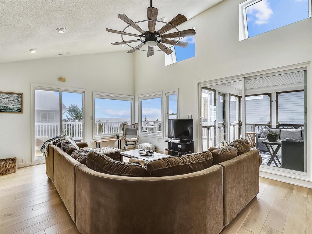 image Spacious living room with a large sectional sofa, TV, and access to the screened porch.