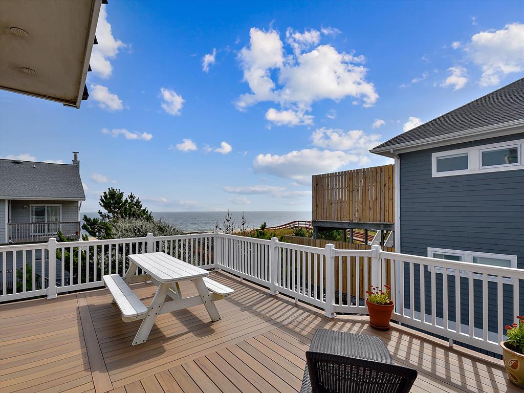 image Spacious balcony with a picnic table and distant views of the ocean and surrounding homes.