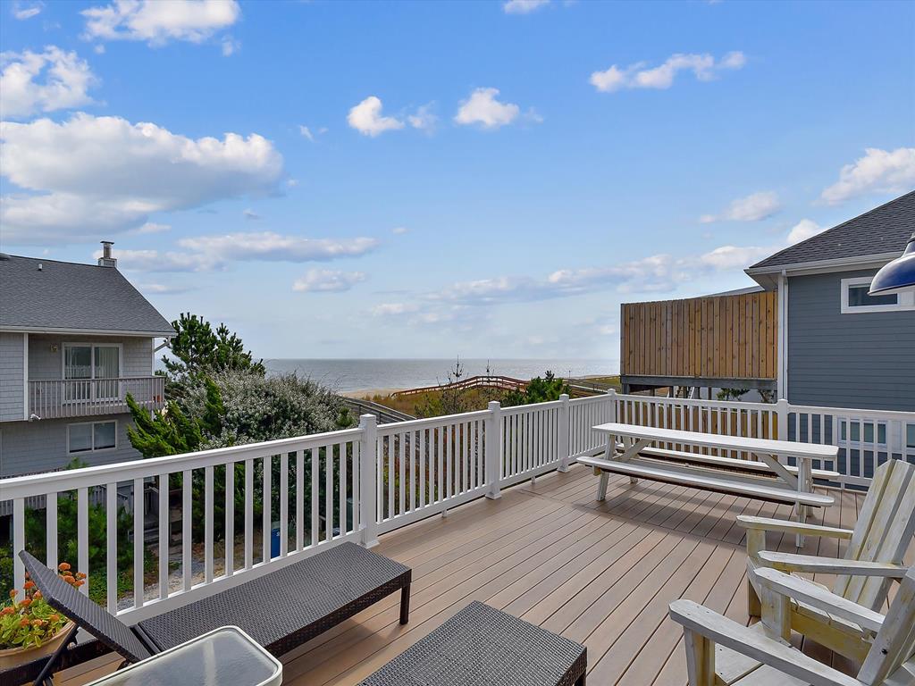 image Elevated deck with seating and views overlooking the nearby beach and coastline.