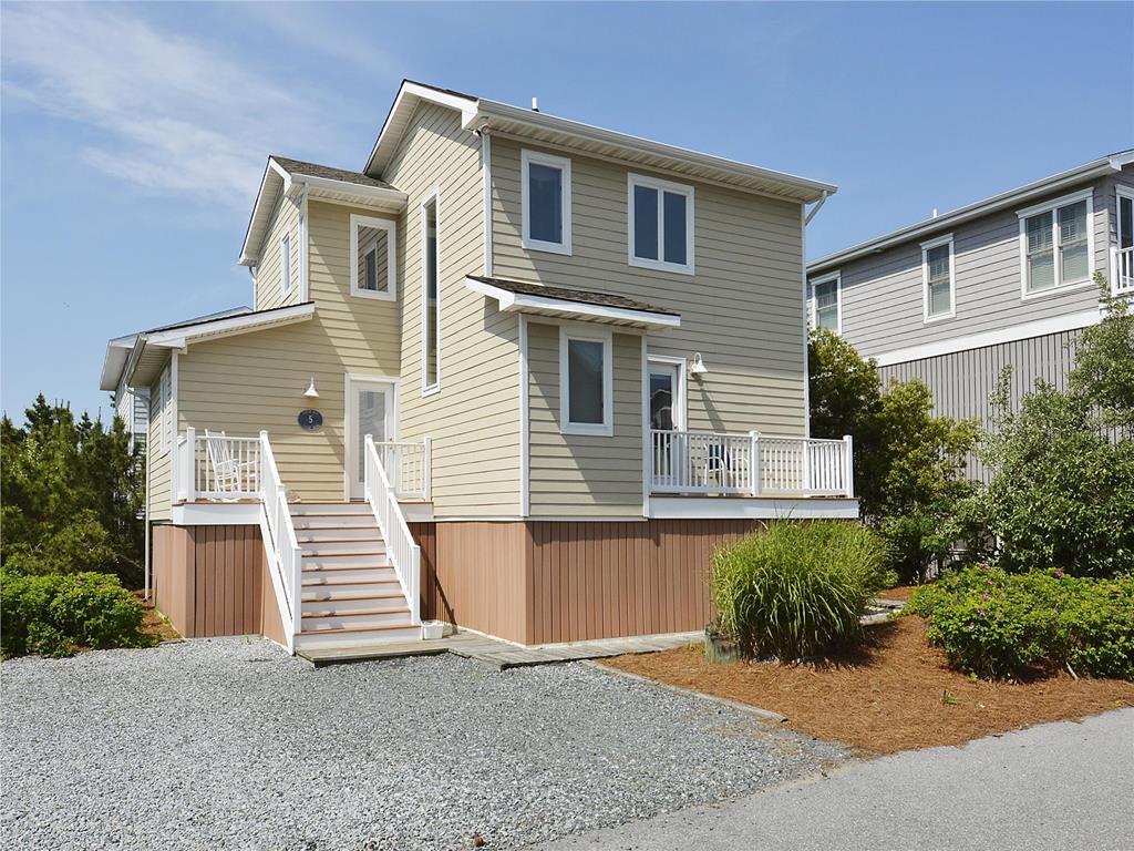 image This charming coastal home showcases a welcoming exterior with a bright façade and inviting steps leading to a spacious porch.