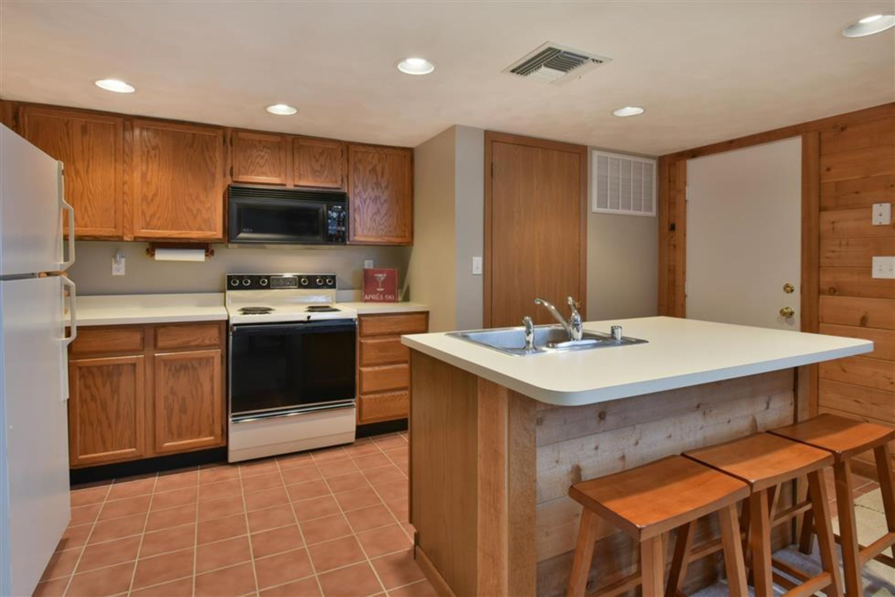 image Fully equipped kitchen with modern appliances and breakfast bar for casual meals and gathering.