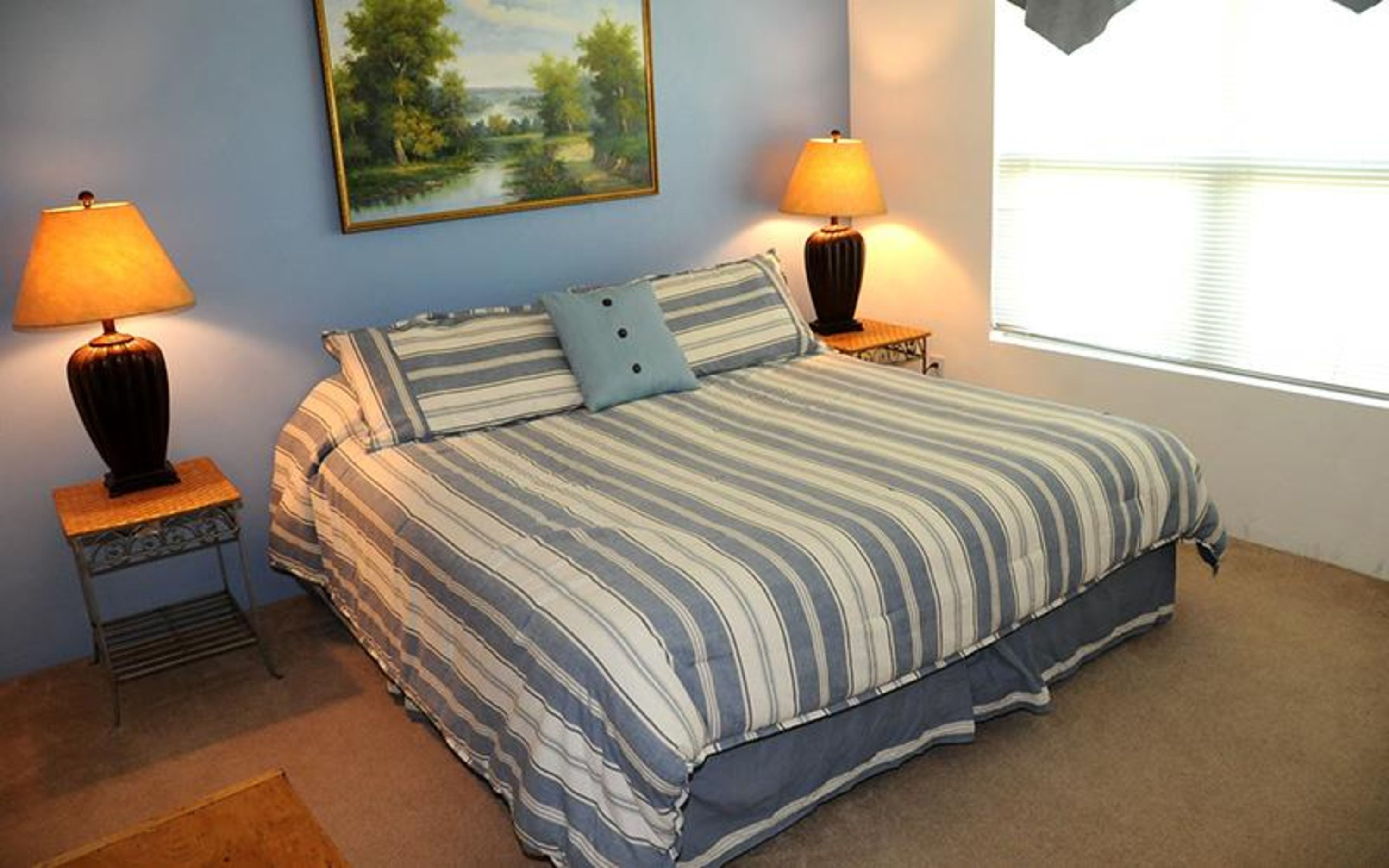 image Comfortable queen bed with striped bedding, warm lighting, and wall art for a homelike feel.