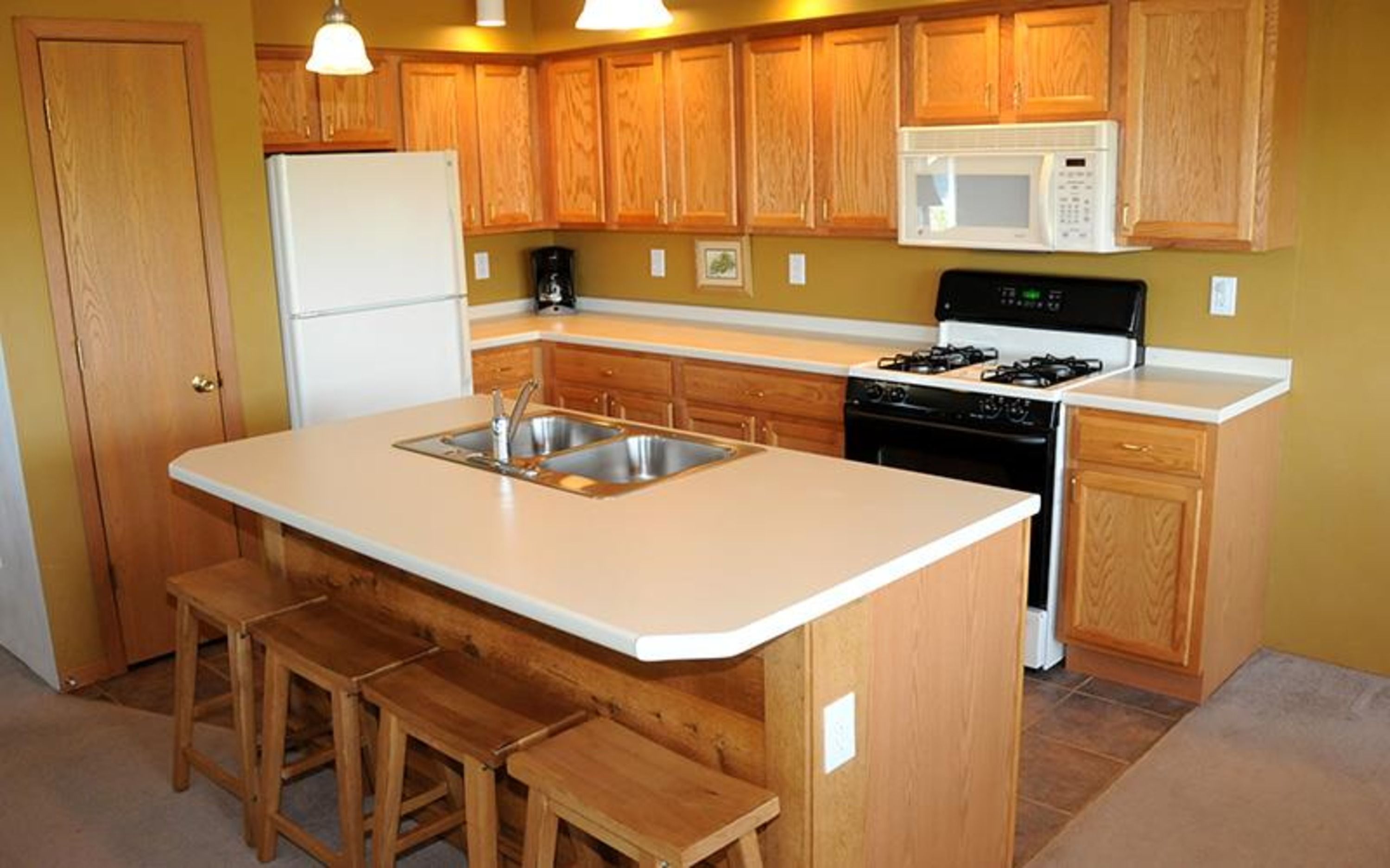 image Fully equipped kitchen with wood cabinetry, appliances, and central island with bar seating.