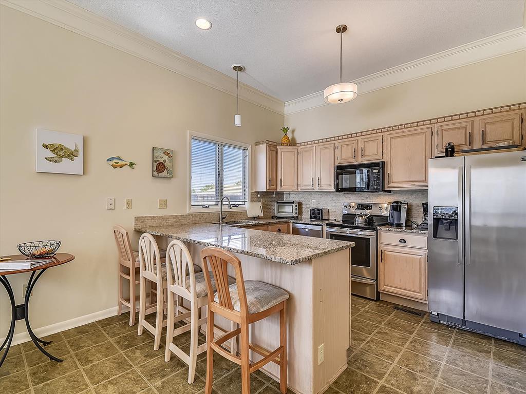 image Fully equipped kitchen with granite countertops, stainless steel appliances, and seating at the island—perfect for easy meals and entertaining.