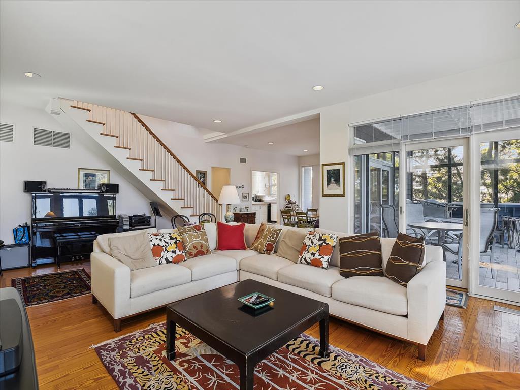 image Cozy living space featuring a plush sectional couch and a piano, with natural light flowing in from the surrounding windows.