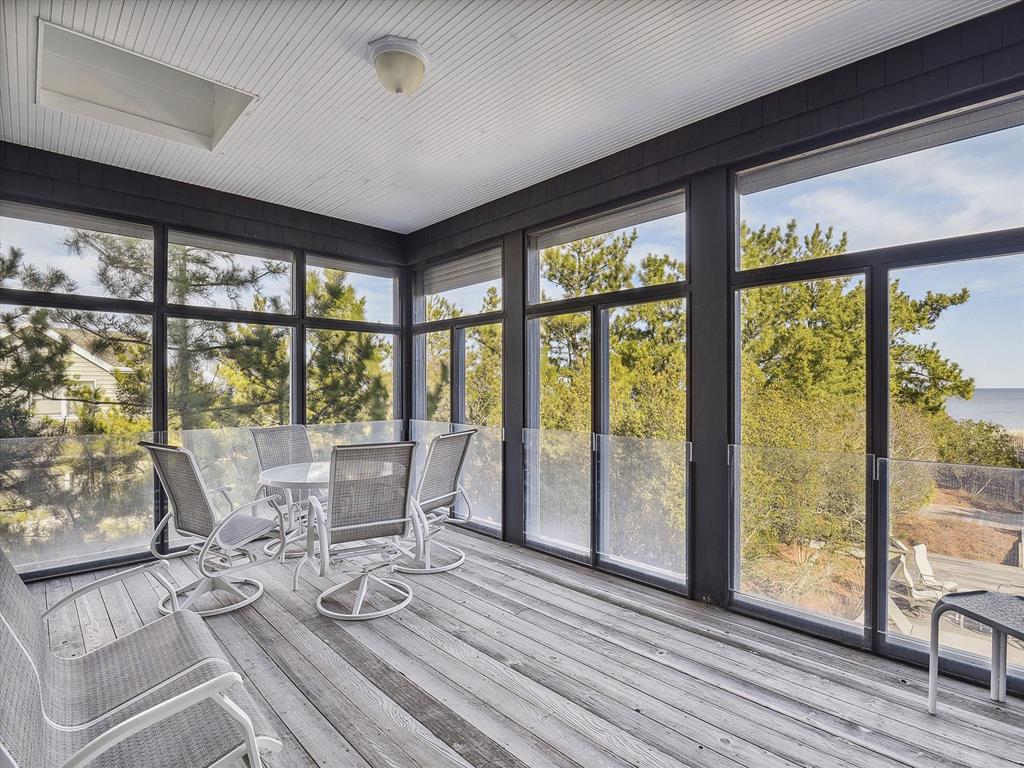 image This bright, screened-in porch boasts comfortable seating and a dining table, surrounded by large windows for a refreshing outdoor ambiance.
