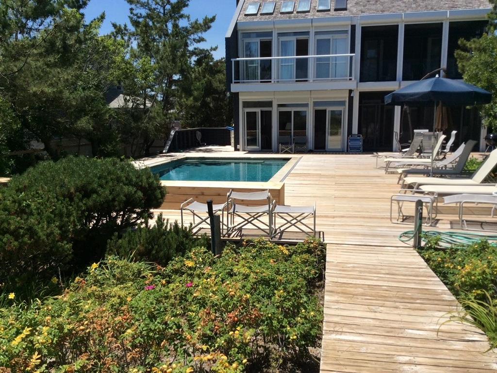 image A stunning outdoor deck showcases a serene swimming pool surrounded by comfortable lounge chairs and colorful flowers for a tranquil ambiance.