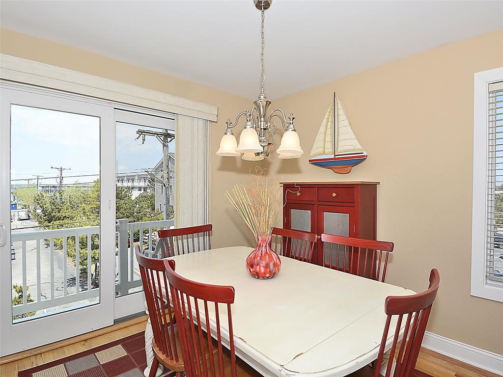 image A dining area with a large table surrounded by red chairs, illuminated by a chandelier, and views outside.