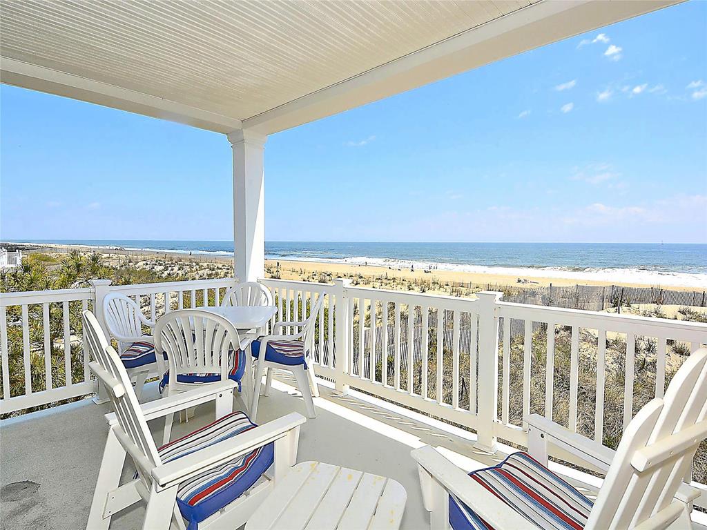 image A view from the balcony showing a table and chairs overlooking the ocean and sandy beach.