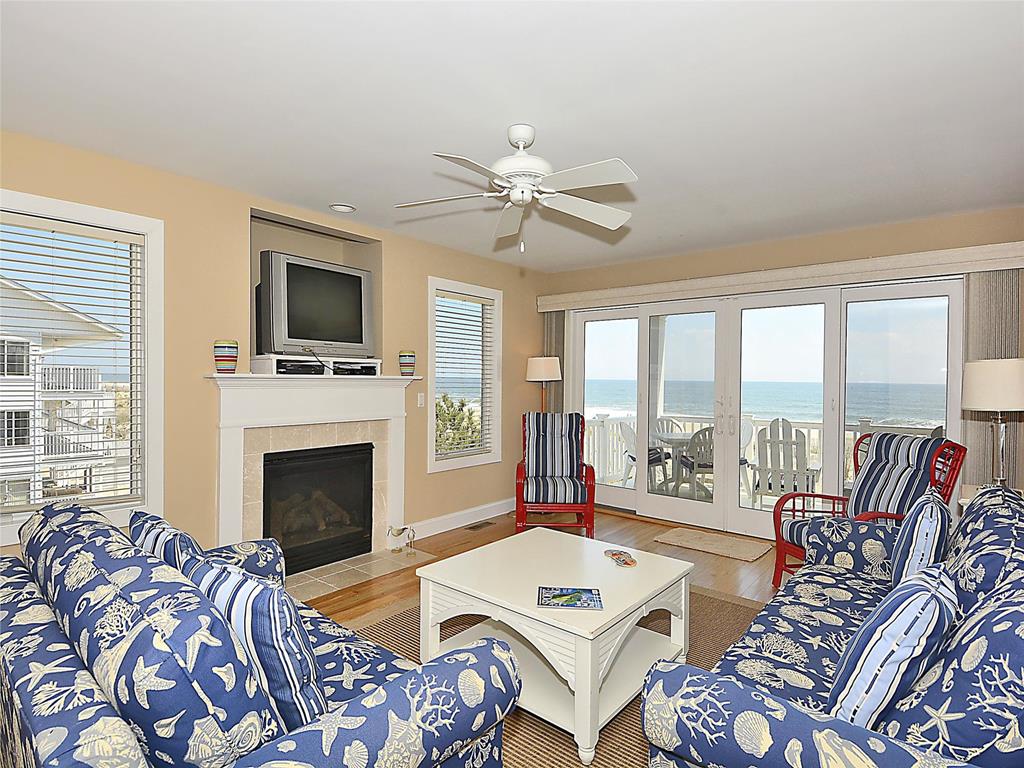 image The living room features patterned sofas, a coffee table, and a view of the ocean through large sliding doors.