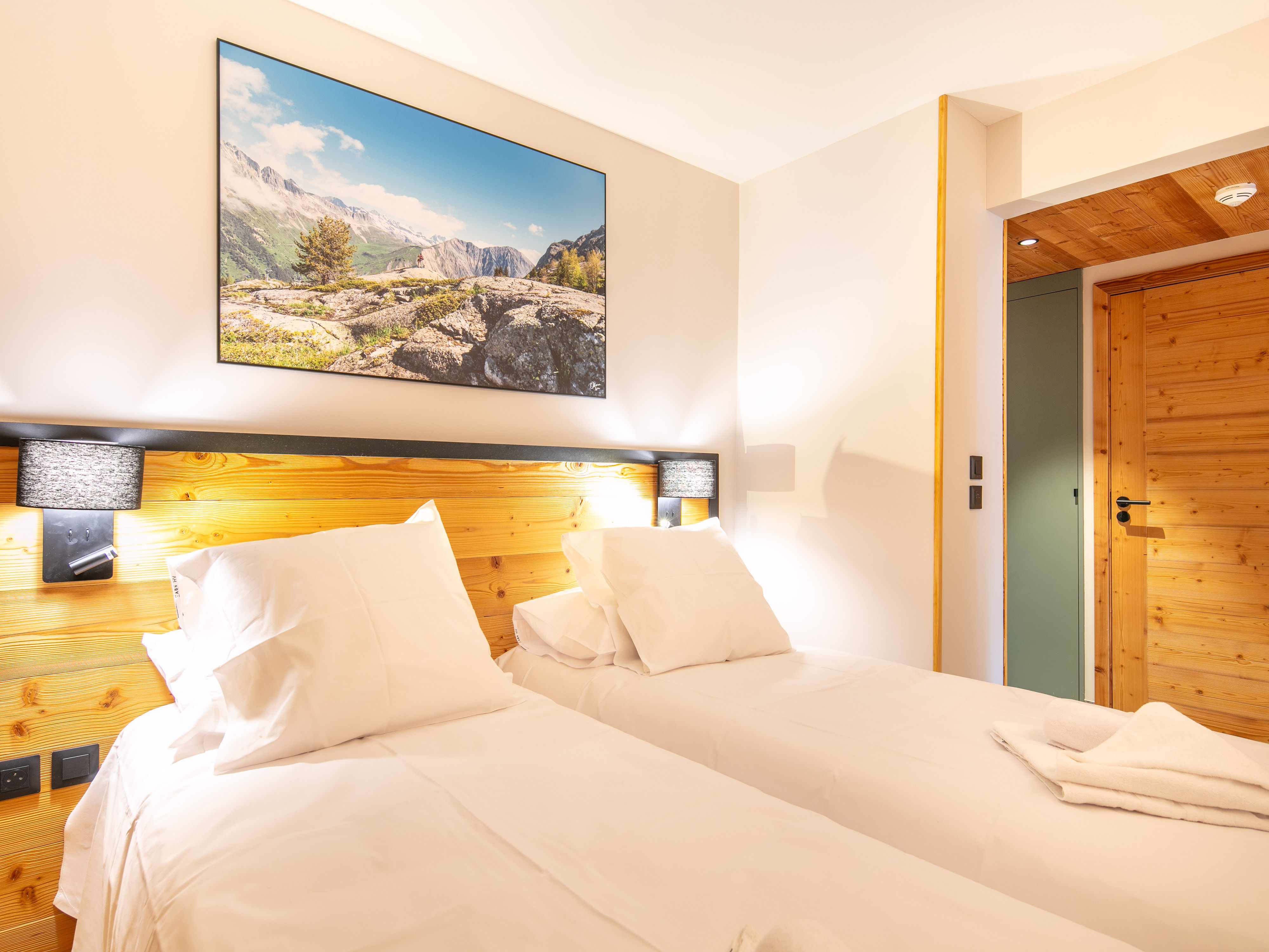 image Unwind in this cozy bedroom featuring comfortable beds and warm wooden accents.