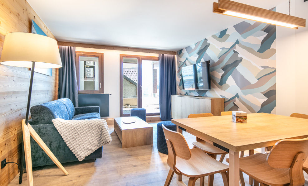 image This stylish living room features a cozy blue sofa, modern decor, and a dining area with a wooden table, perfect for relaxing after a day of exploring Vaujany.