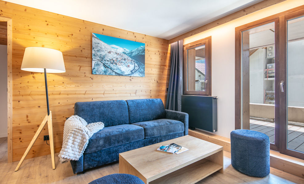 image The cozy living room features a plush blue sofa, wooden walls, and large windows that let in natural light.