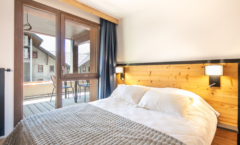 image The cozy bedroom features a comfortable bed, wooden accents, and a balcony that invites natural light into the space.