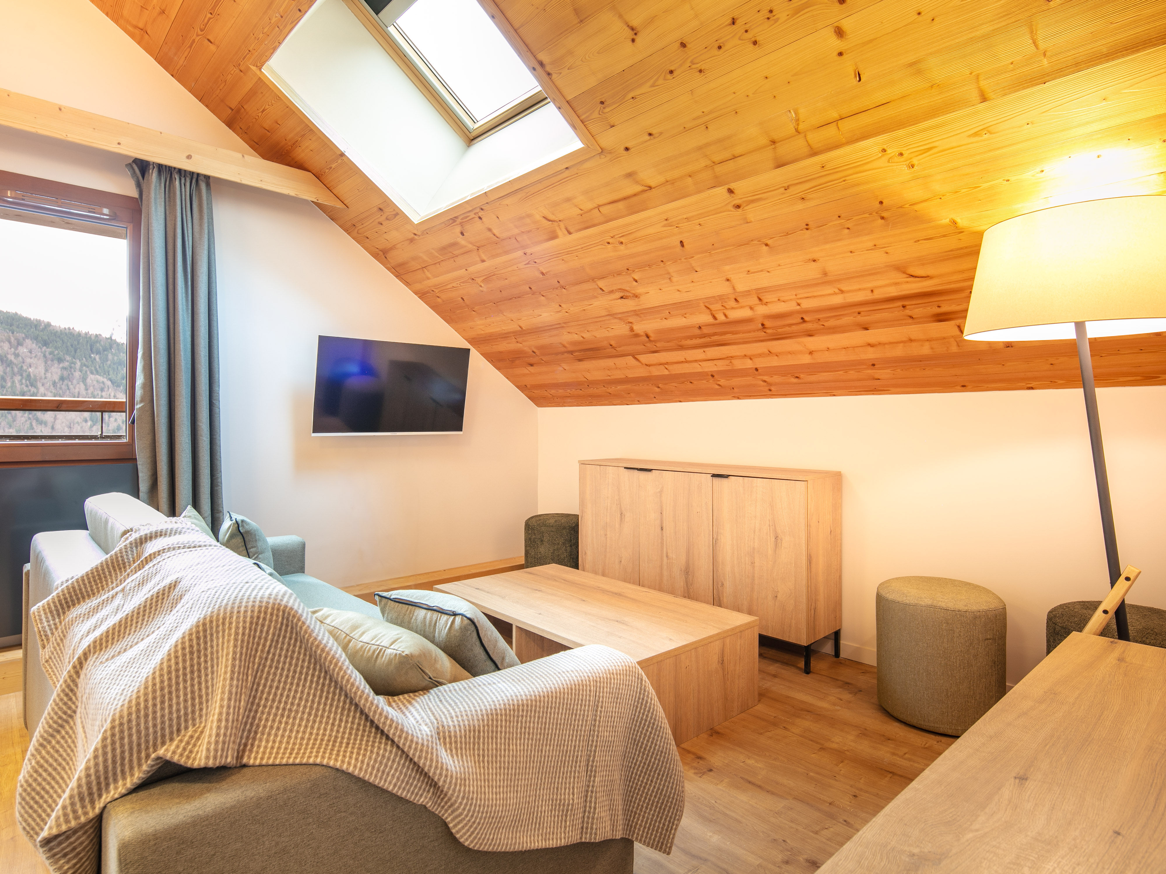 image Relax in the inviting living space with a comfy sofa, sleek TV, and natural light flooding through the skylight.