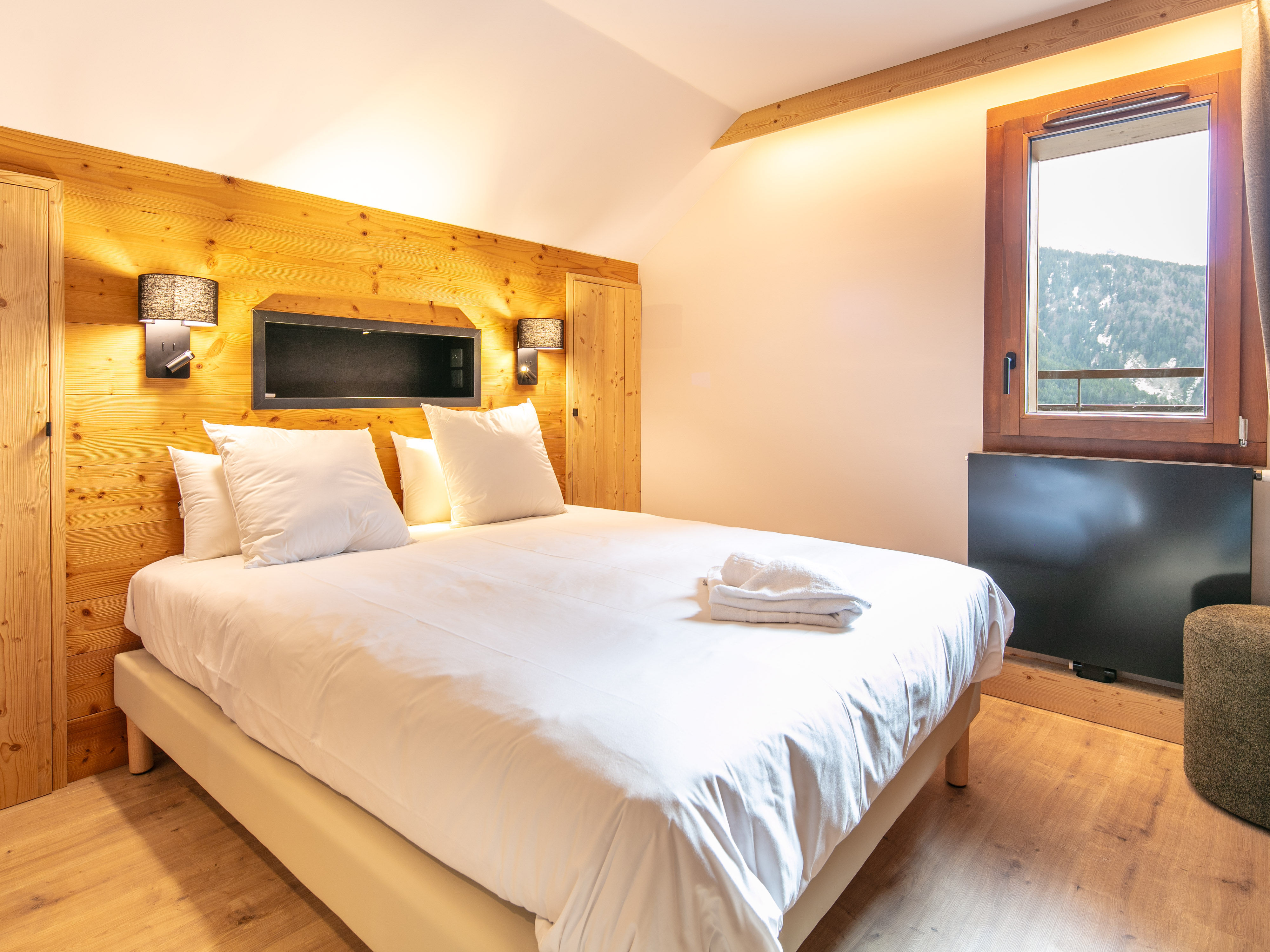 image Relax in this cozy bedroom adorned with warm wood accents and soft lighting.