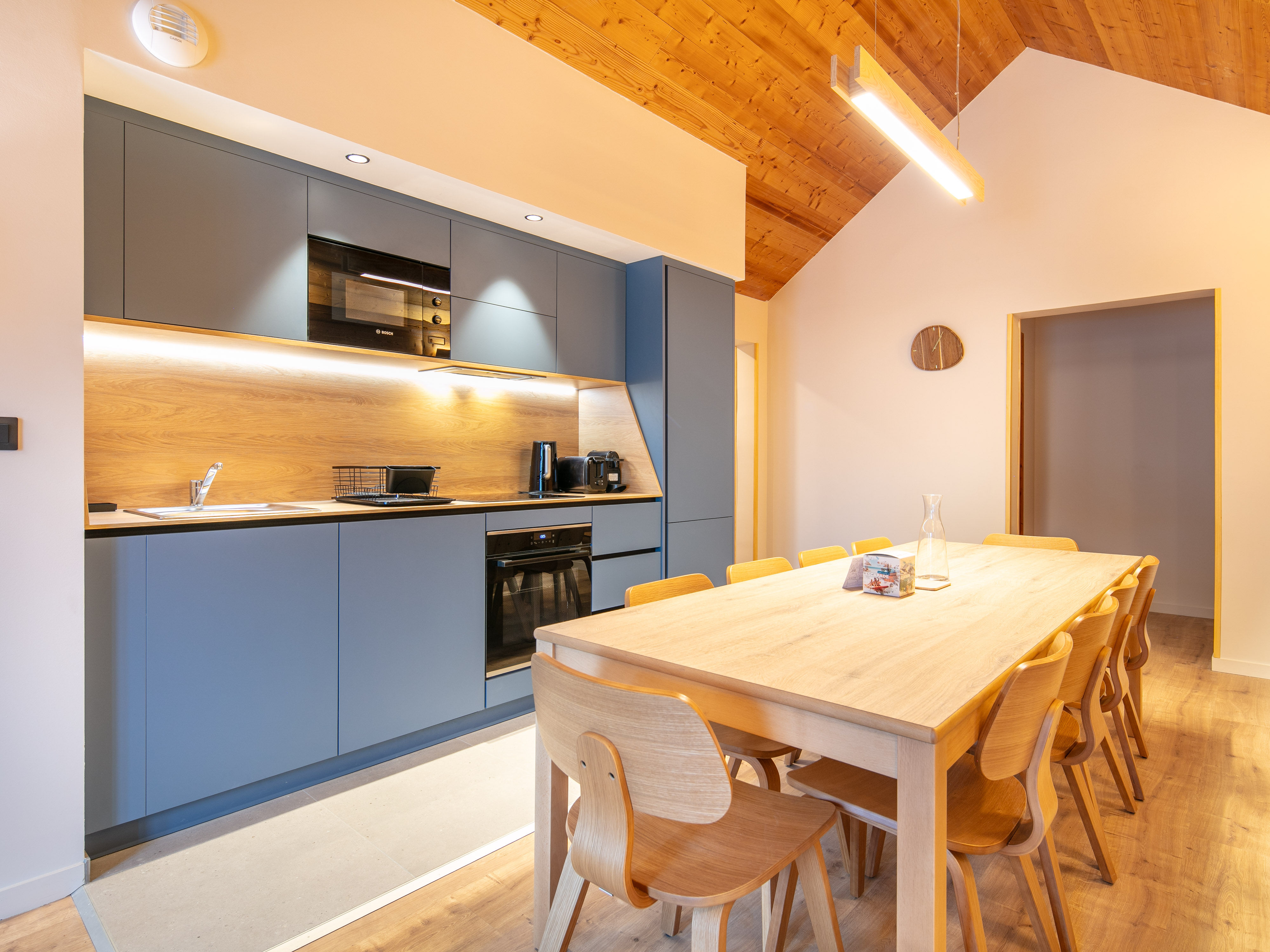 image Gather around a spacious dining table in a modern kitchen, perfect for shared meals and memorable conversations.