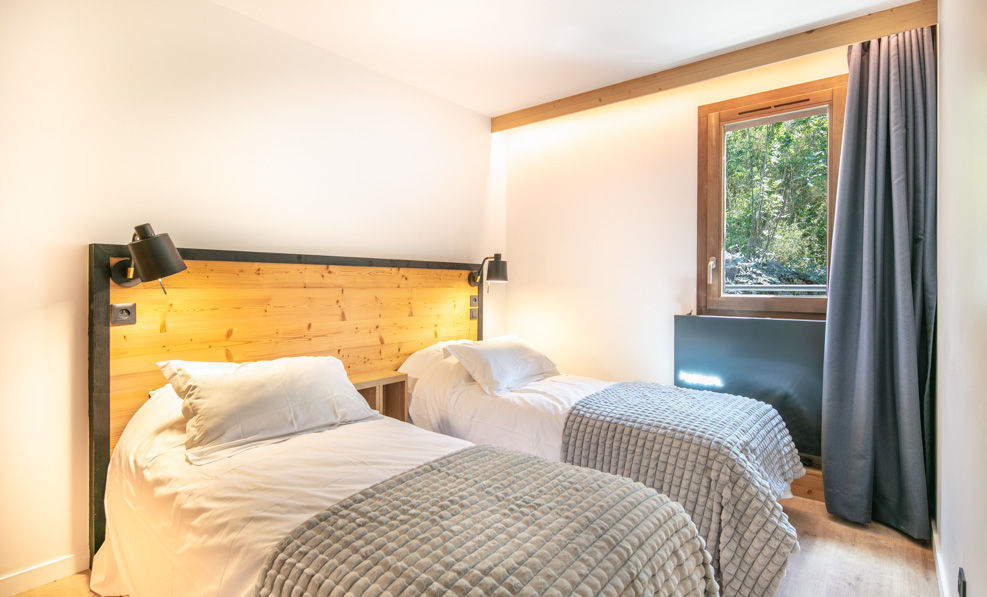 image Natural light floods the second bedroom, highlighting the comfortable twin beds and tranquil decor.