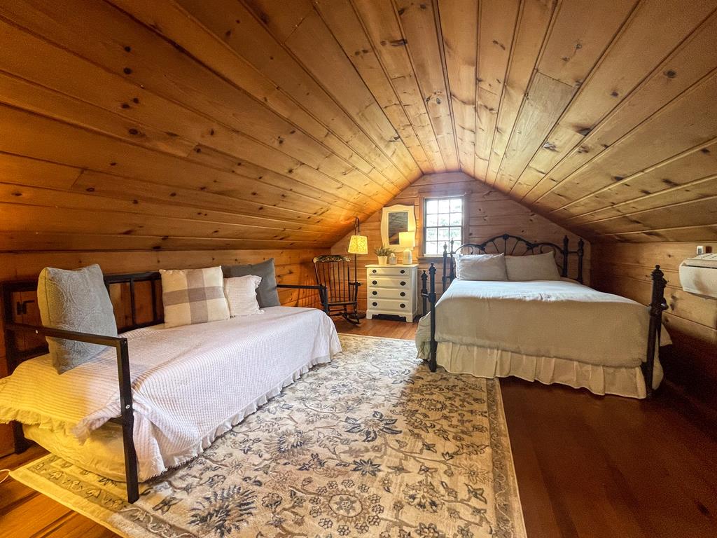 image Tucked beneath a warm pine ceiling, this upstairs bedroom feels like a storybook hideaway — perfect for a peaceful night’s sleep after a beach day.