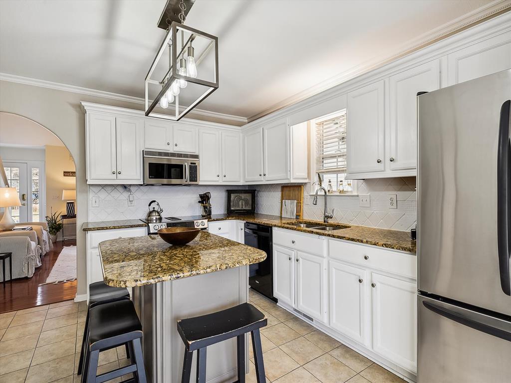 image Cook family favorites in the open kitchen featuring a spacious island, stainless-steel appliances, and bright coastal finishes.