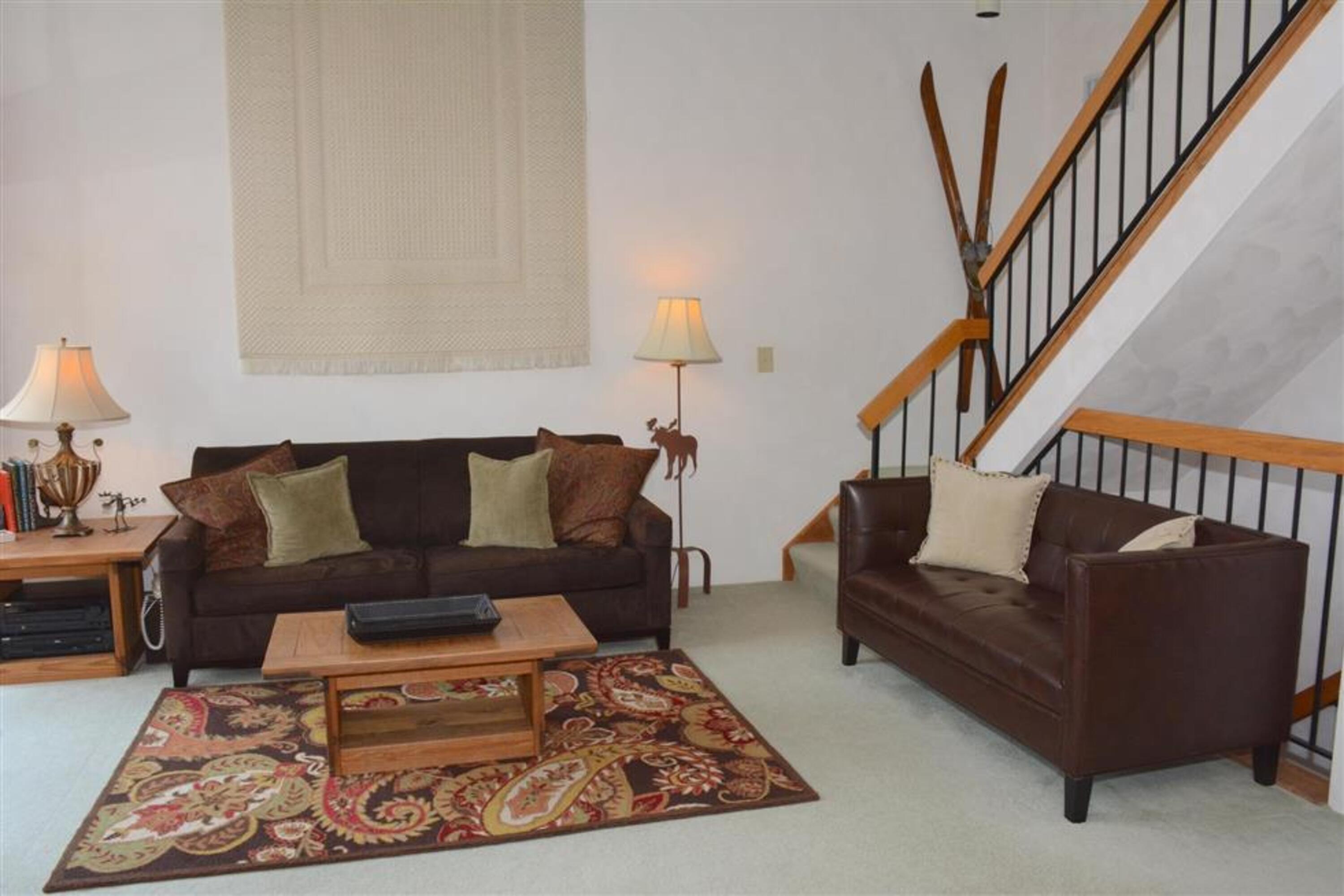 image Spacious main living area featuring cozy seating and access to the upper loft bedroom.