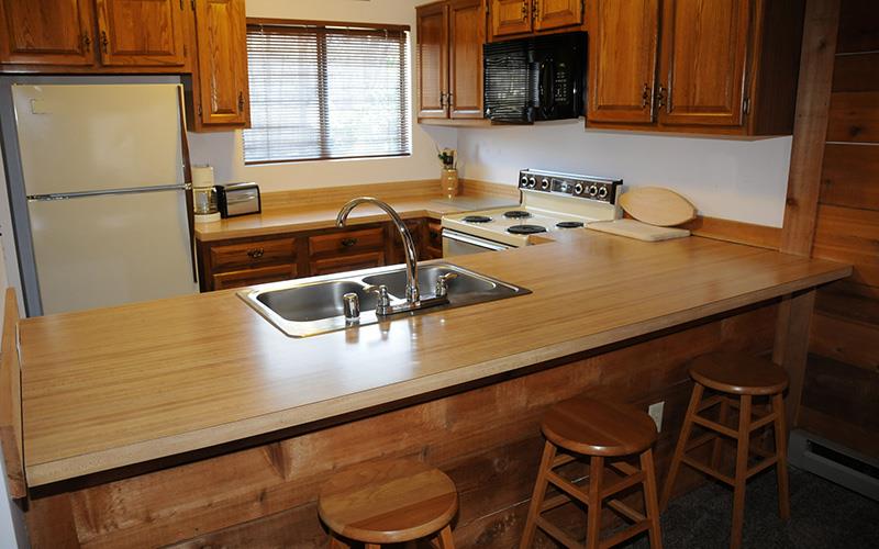image Fully equipped kitchen with breakfast bar seating and adjacent dining area.