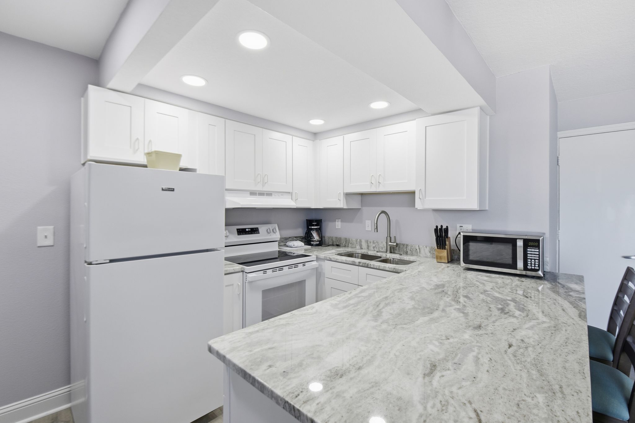 image The kitchen beckons culinary creativity, boasting pristine white cabinetry, gleaming granite countertops, and essential appliances, all set against a tranquil backdrop.