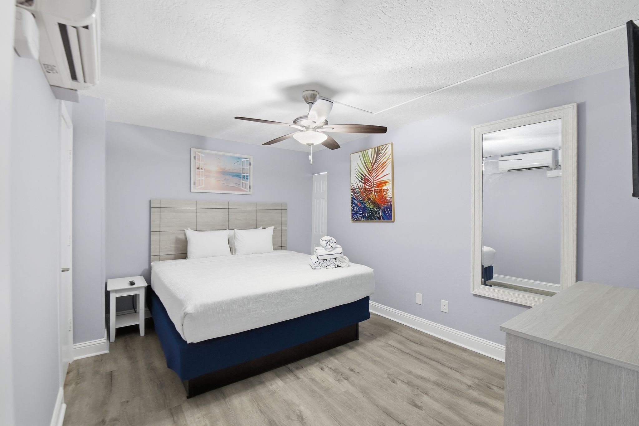 image A serene retreat, the bedroom features a plush queen-sized bed adorned with fresh linens, complemented by vibrant artwork and ample storage solutions for a comfortable stay.