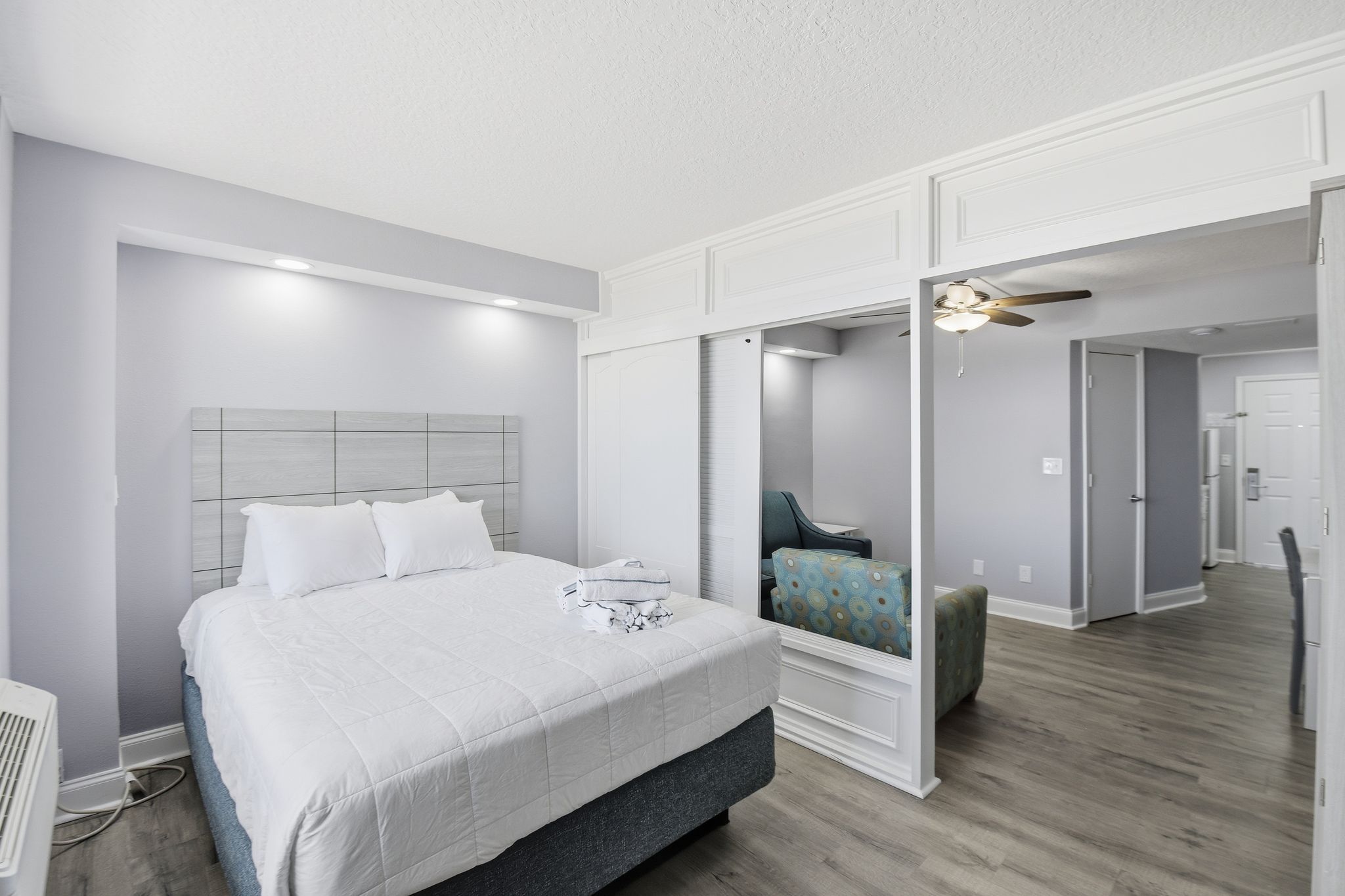 image A serene sleeping area showcases a plush queen bed with soft linens, complemented by tasteful décor and natural light flooding through the large window overlooking the ocean.