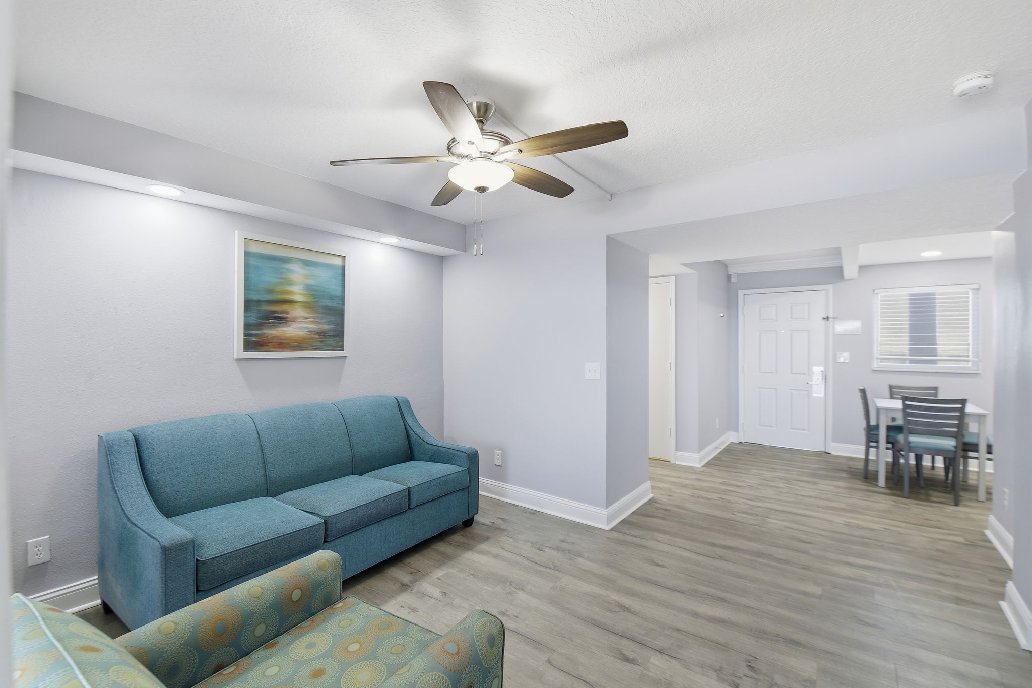 image The spacious living area features a cozy blue sofa complemented by contemporary decor, creating an inviting space for relaxation after a day on the beach.