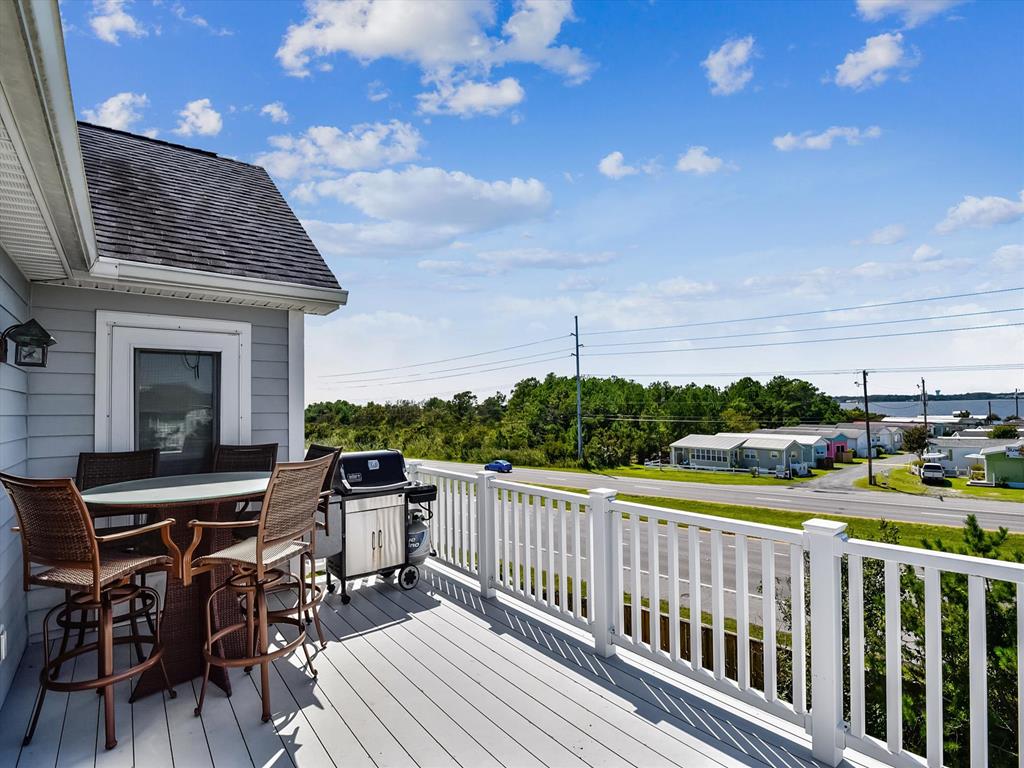image This spacious balcony features stylish wicker seating and a grill, perfect for enjoying coastal breezes while overlooking the lush greenery and distant views of the beach.